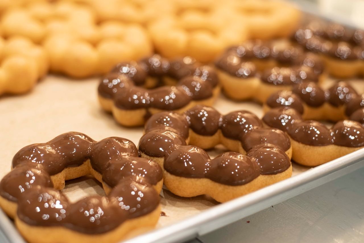 Services Freshly baked chocolate glazed mochi donuts on a tray in a San Francisco bakery.